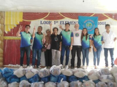 The World March base Team with key barangay (community) officials . In the foreground are the bags of food to be shared with school children who most need it.